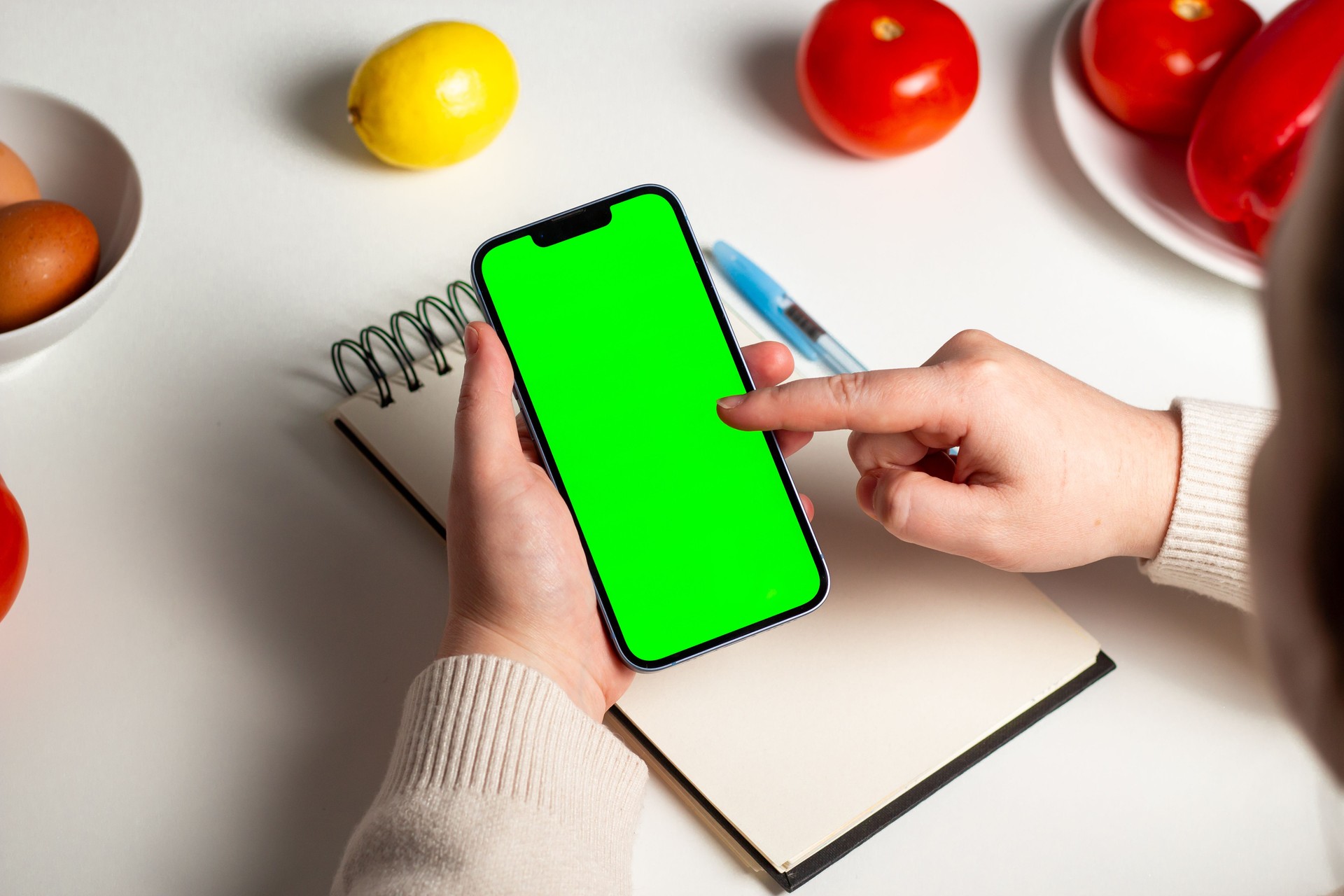 Overhead shot of female creating diet plan for weight loss. Mock up notebook and green screen. Design for healthy lifestyle app, website and nutritionist.
