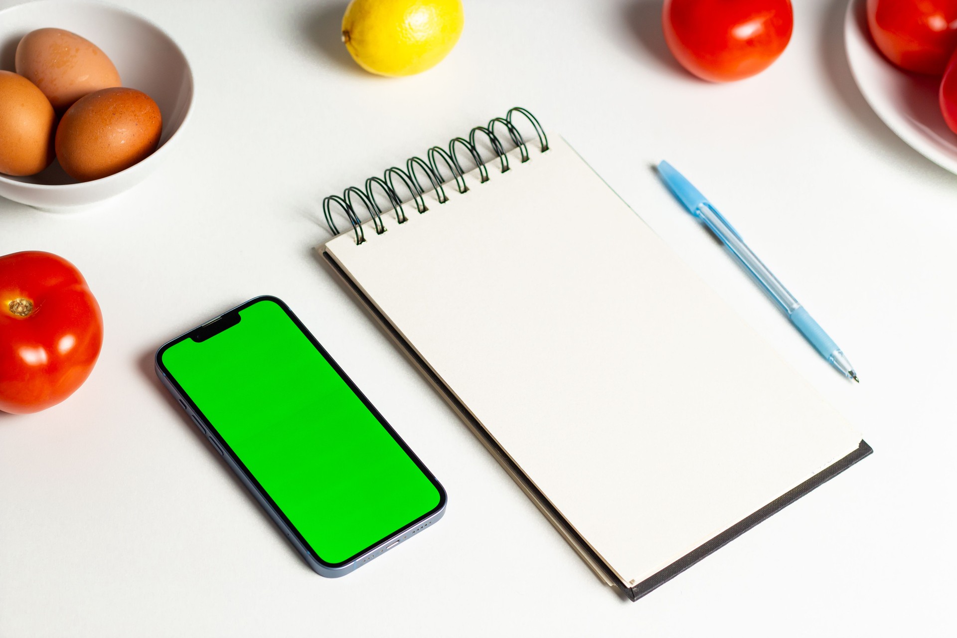 Overhead shot of female creating diet plan for weight loss. Mock up notebook and green screen. Design for healthy lifestyle app, website and nutritionist.